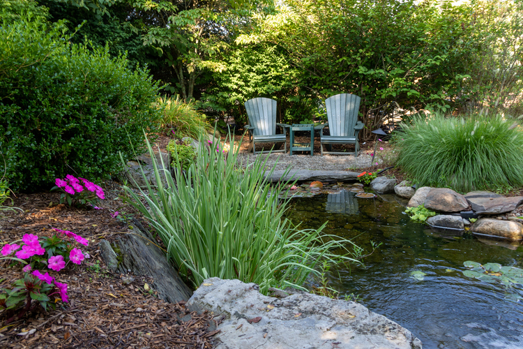Udoban kutak za sedenje u maloj bašti ispunjenom zelenilom i zvukom vode